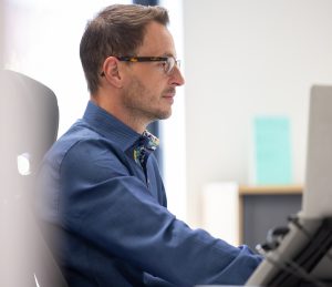 Outsourced HR Support Services in London with a side view of a man sat at desk